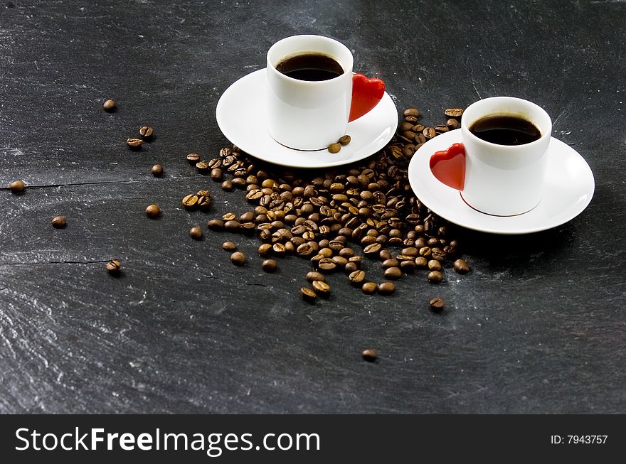 Espresso served on heart shaped cup on coffee beans