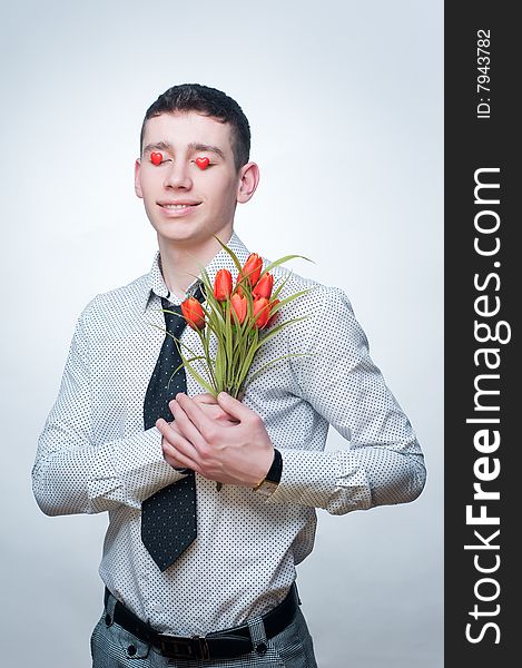 Romantic man with tulips and heart-shaped candies over his eyes