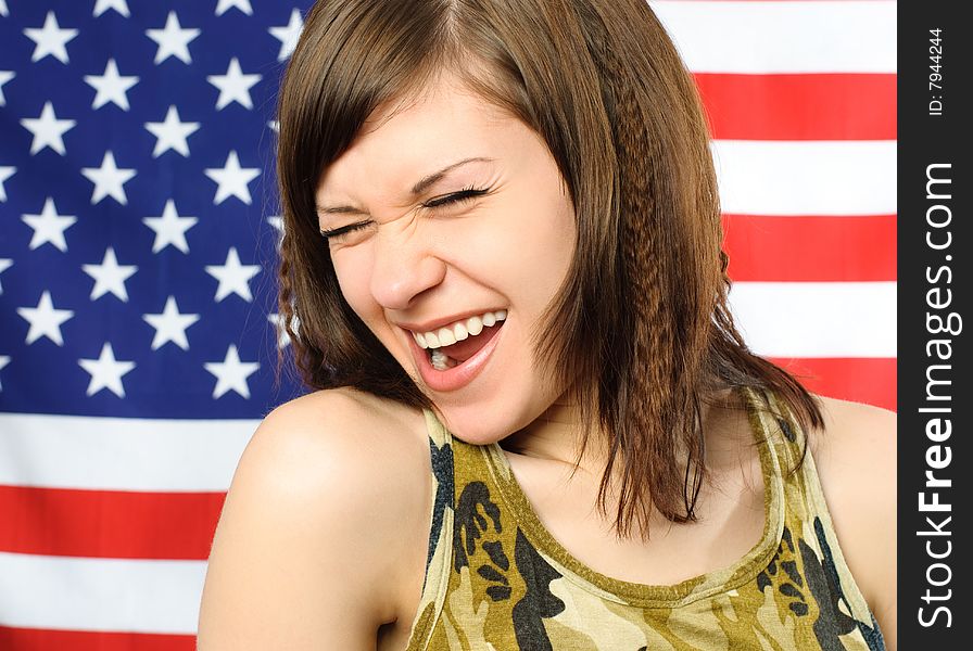 Happy laughing young woman standing opposite an American flag. Happy laughing young woman standing opposite an American flag