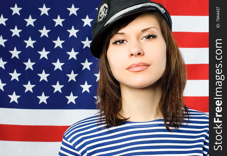 Beautiful young confident sailor standing near the American flag. Beautiful young confident sailor standing near the American flag