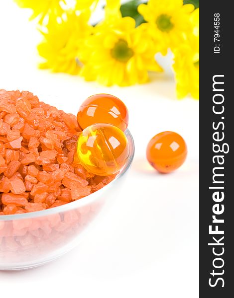 Spa pruducts: bath salt, oil balls in a bowl and yellow flowers