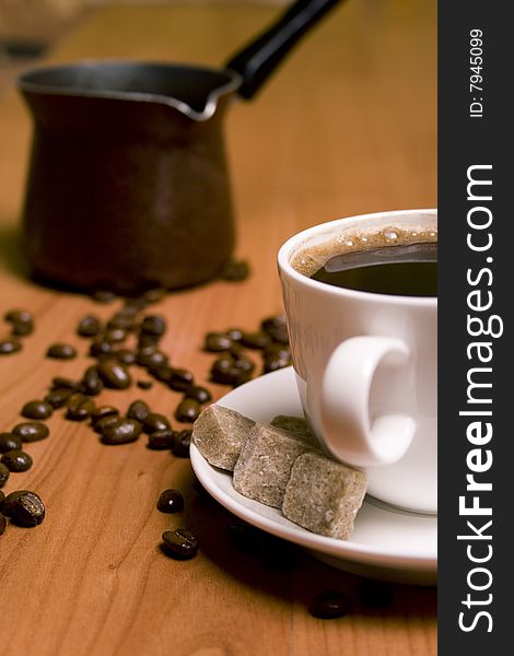 Cup of coffee, caffee-maker, sugar and beans on wooden table. Cup of coffee, caffee-maker, sugar and beans on wooden table