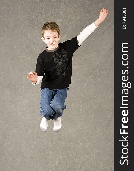 Little boy leaping into air over gray background. Little boy leaping into air over gray background