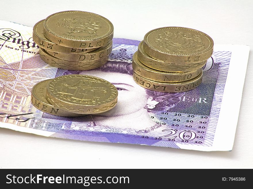 British pound  coins on top of a twenty pound note. British pound  coins on top of a twenty pound note