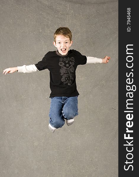 Little boy leaping in air, over gray background