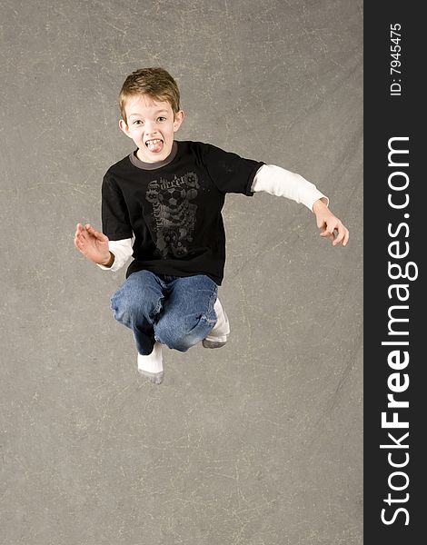 Little boy jumping into air over gray background