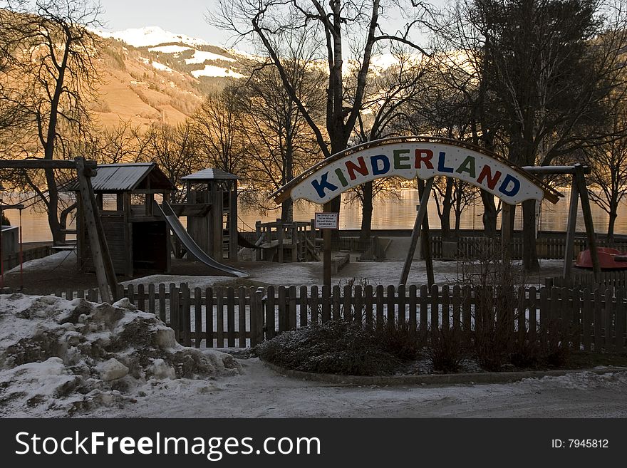 A frozen playground in shade with brightly lit mountains in the background