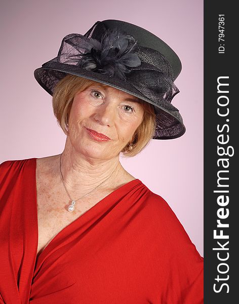 Portrait of very attractive older woman wearing black hat and red dress. Portrait of very attractive older woman wearing black hat and red dress