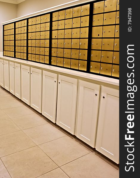 Rows of indoor brass mailboxes above locked cabinets. Rows of indoor brass mailboxes above locked cabinets
