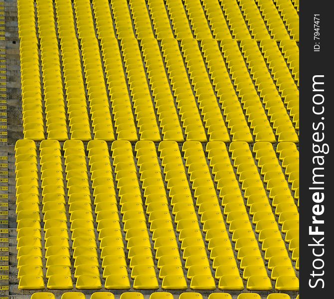 Rows and rows of yellow stadium seats on an incline creating an urban abstract
