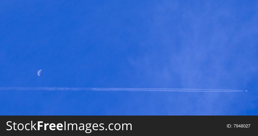 Plane flying through a blue sky with a half moon. Plane flying through a blue sky with a half moon