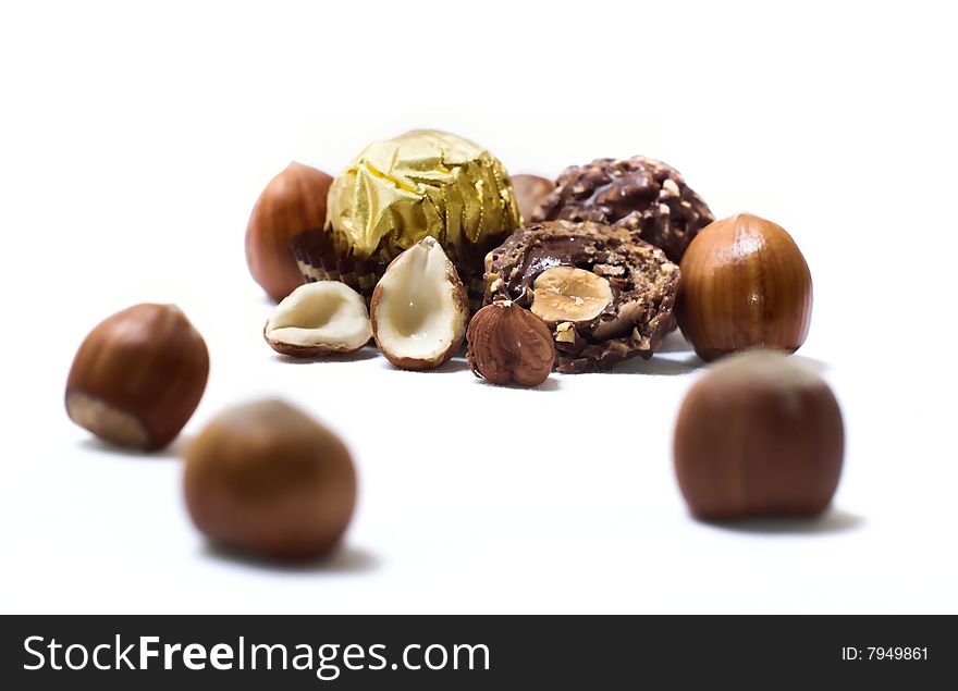 Haselnuts, pralines in focus,isolated on white. Haselnuts, pralines in focus,isolated on white