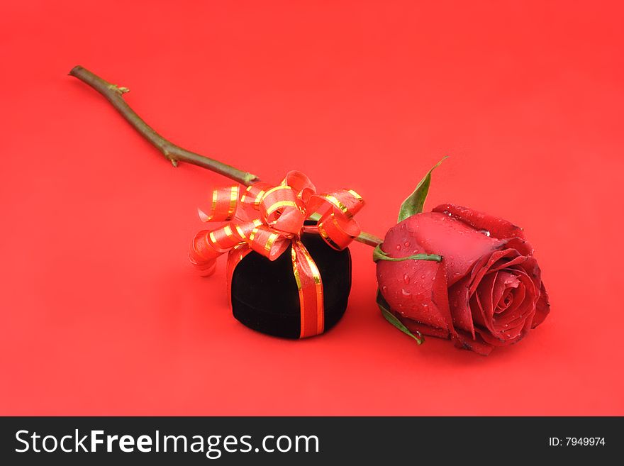 Red rose and black gift box on the red background. Red rose and black gift box on the red background.