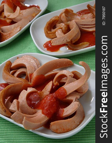 Fresh sausages poured with ketchup on plate