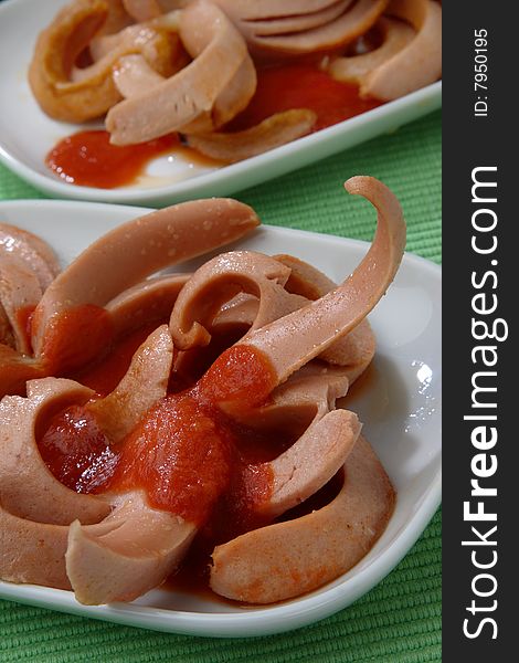 Fresh sausages poured with ketchup on plate