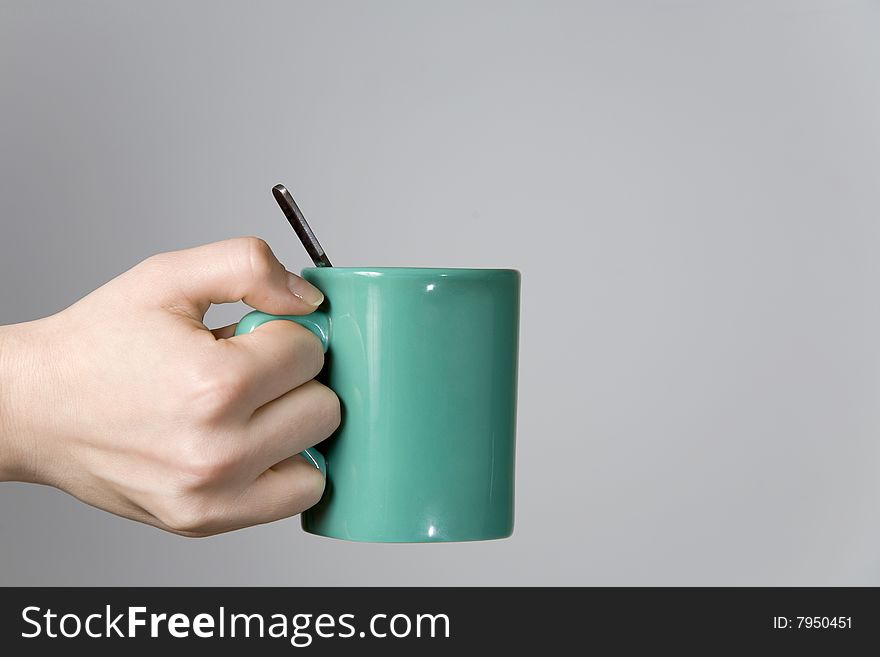 Woman hand holding a tea cup with a spoon close-up