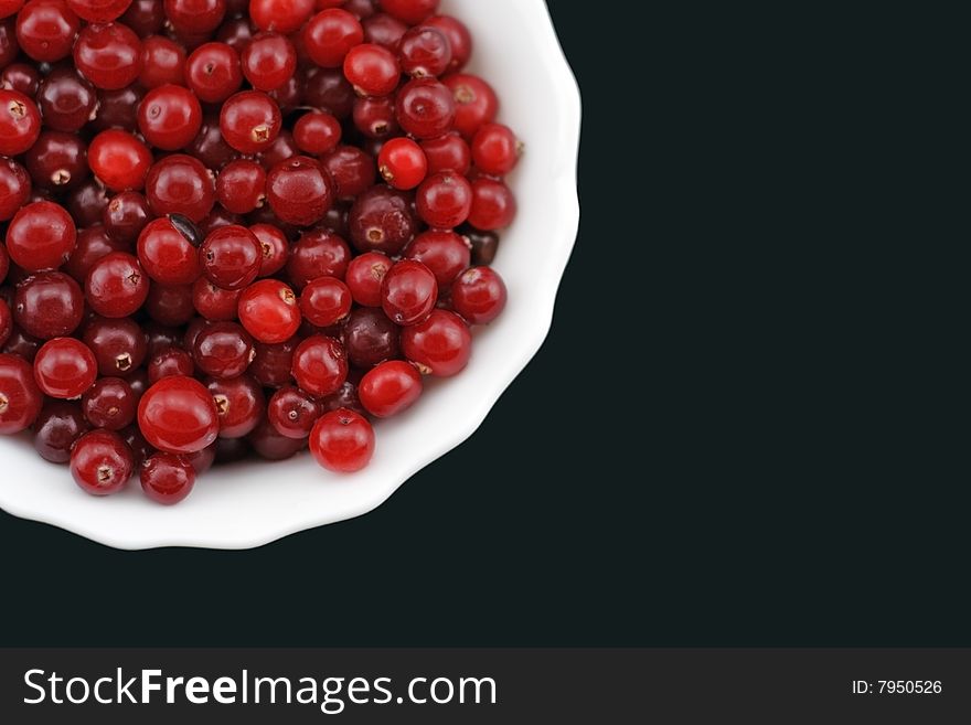 Fresh cranberry on a plate. The top view. Black background.