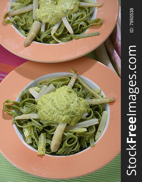 Green noodles with white asparagus and sauce on plate