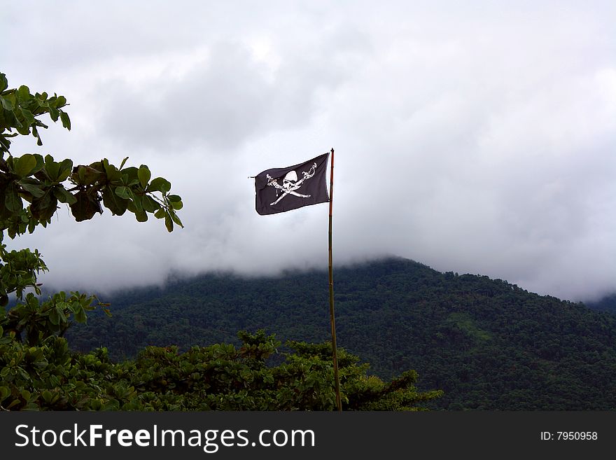 Pirate flag in a remote island, with a foggy sky. Pirate flag in a remote island, with a foggy sky.