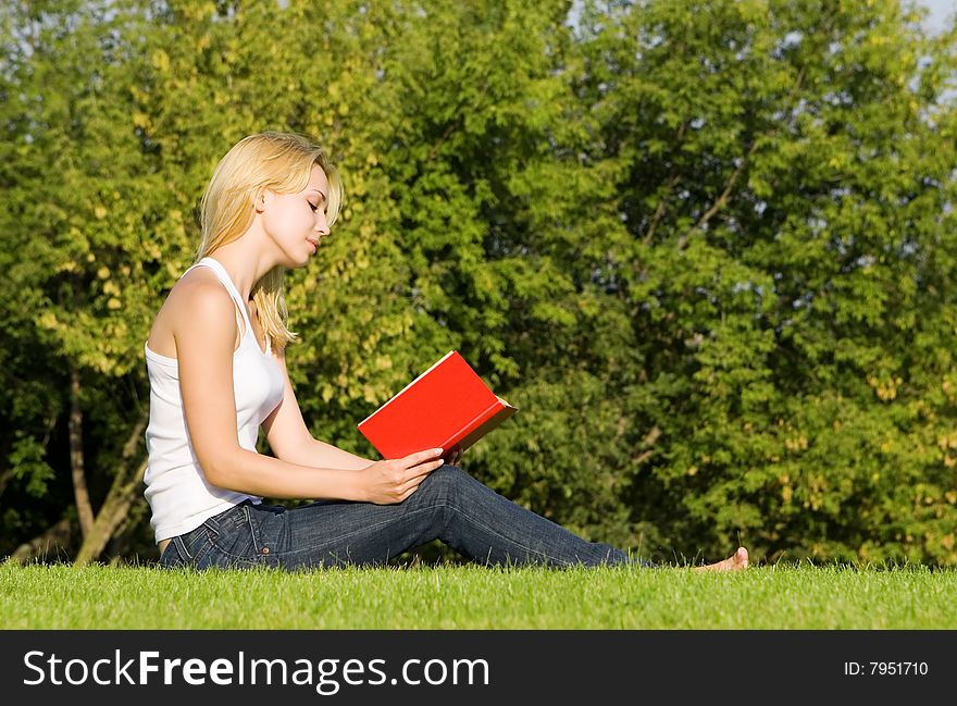 Young blonde reads book in the park