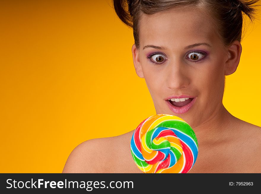 Sexy brunette woman with lollipop on yellow background