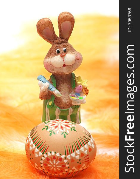 Easter bunny with easter egg on orange and yellow feathers