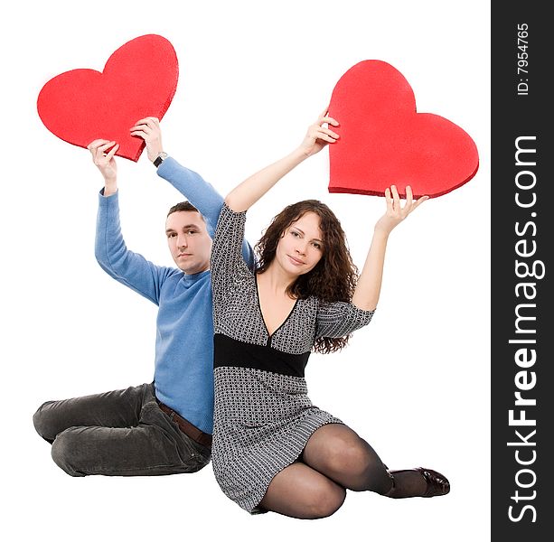 Couple sitting holding red hearts  isolated over white background