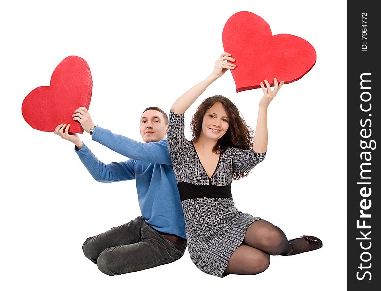 Couple sitting holding hearts  isolated over white background
