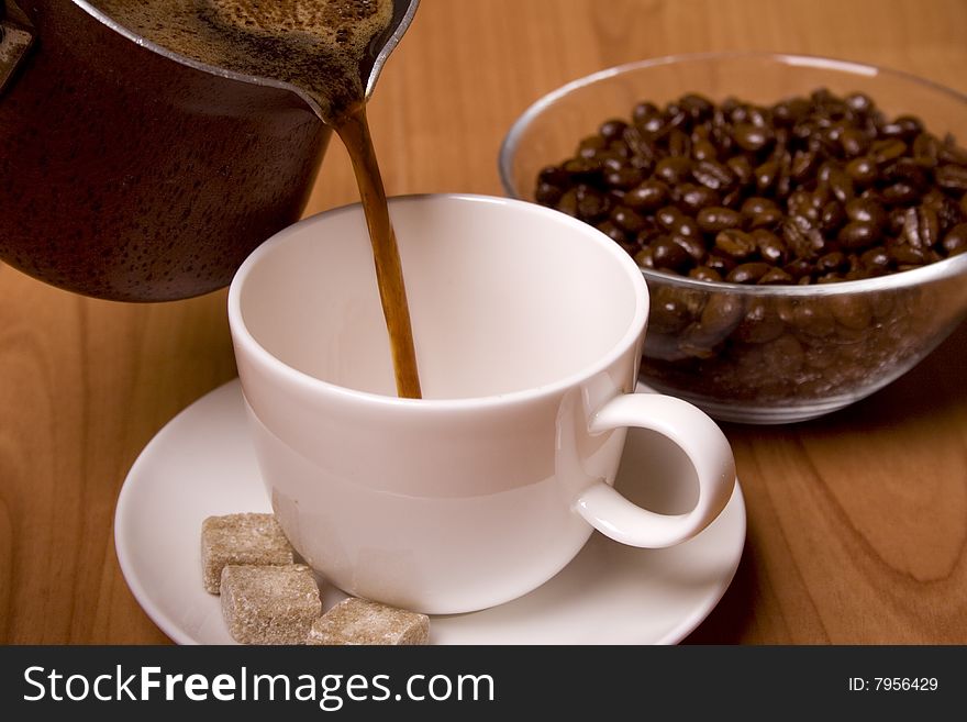 Cup of coffee, sugar and beans in glass bowl on wooden table