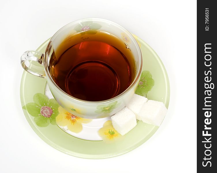 Tea cup on a saucer with sugar and green ornament