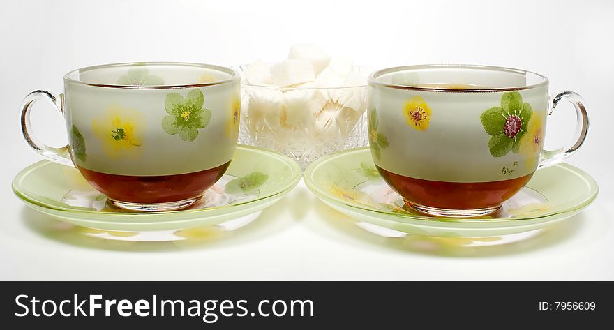 Two tea cups on a saucer with sugar