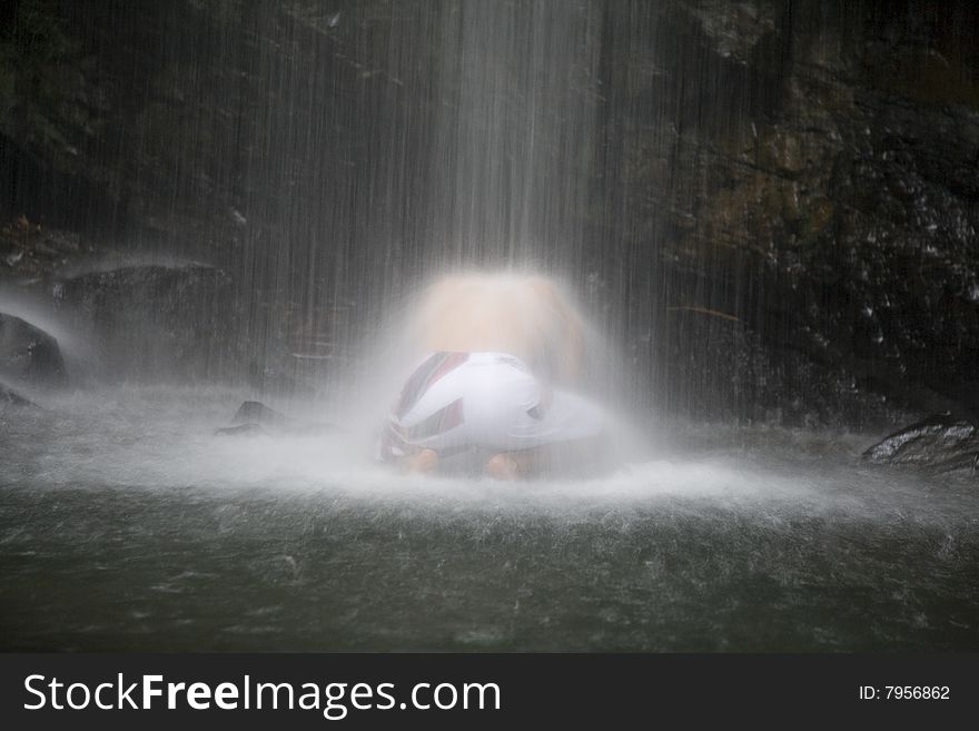 A young man gets a massage from a waterfall. A young man gets a massage from a waterfall