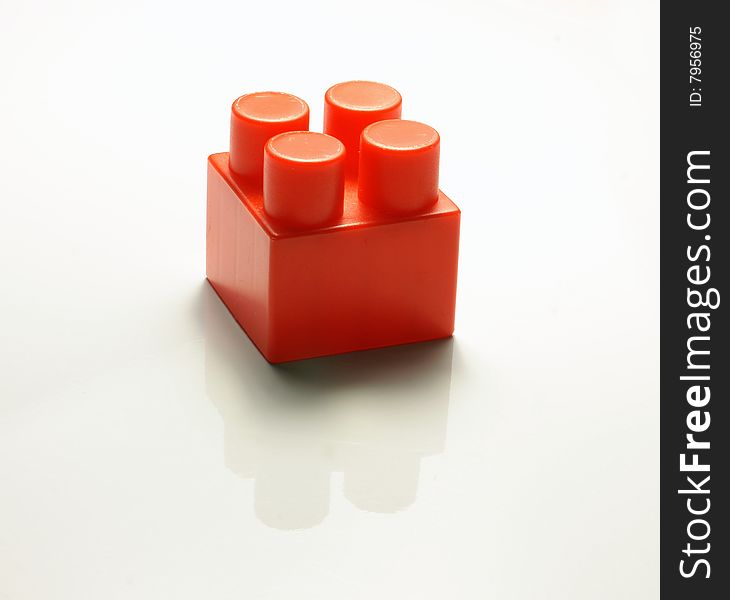 One red cube from the children's designer on a white background with a shade and reflexion
