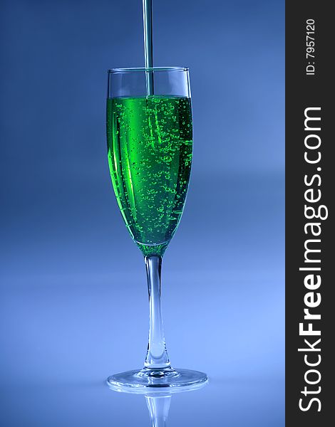 Green drink in glass against blue background. Green drink in glass against blue background