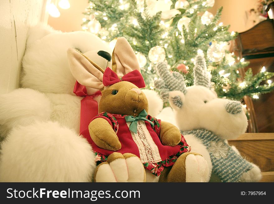 Several stuffed animals sit in front of a Christmas tree. Several stuffed animals sit in front of a Christmas tree.