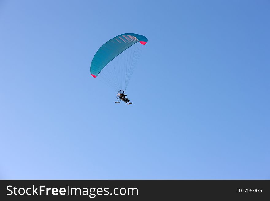 Paraplane flying, wide shot over blue sky
