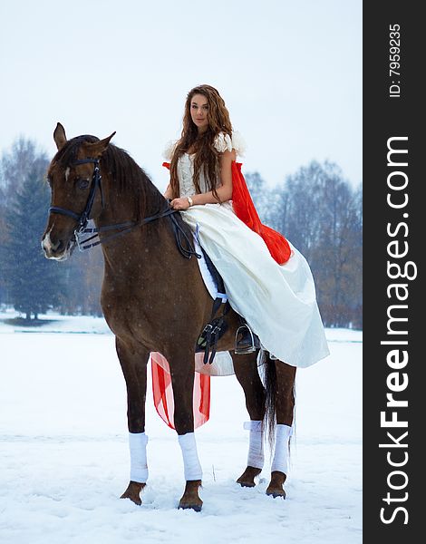 Woman in a white dress in winter on a horse. Woman in a white dress in winter on a horse