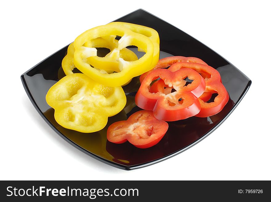 Slices of red and yellow pepper on a black plate on a white background