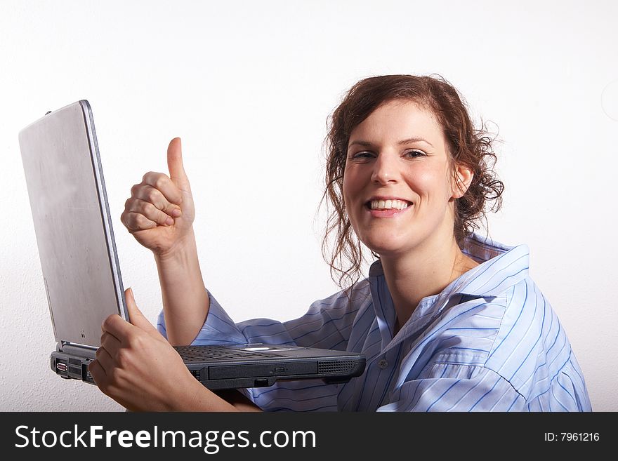 A young woman at home sitting on the floor with her laptop. She is very happy and gives a thumb up sign. A young woman at home sitting on the floor with her laptop. She is very happy and gives a thumb up sign.