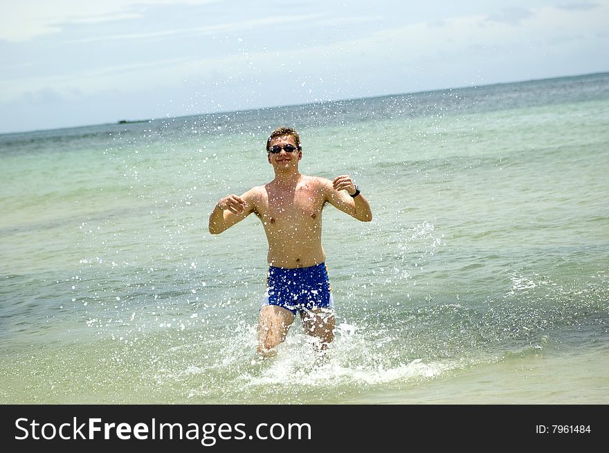 Indonesia, Bali Island holiday. Happy male model playing with water in Indian Ocean.