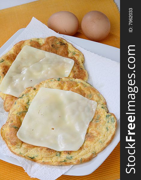 Baked egg omelette with herbs and cheese slices on top on plate