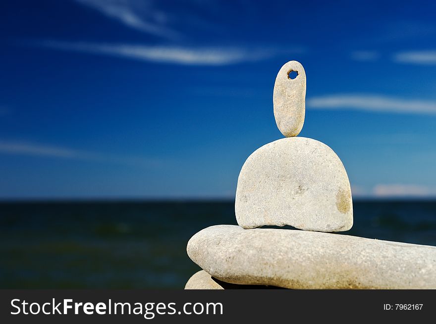 The sea pebble balances at stone top at midday. The sea pebble balances at stone top at midday