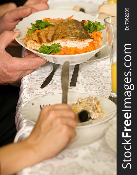 Banquet. Hands hold a plate with a fried salmon.