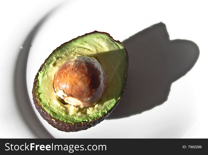 Fresh .Textured.Half avocado with seed on the plate ready to be consumed. Fresh .Textured.Half avocado with seed on the plate ready to be consumed