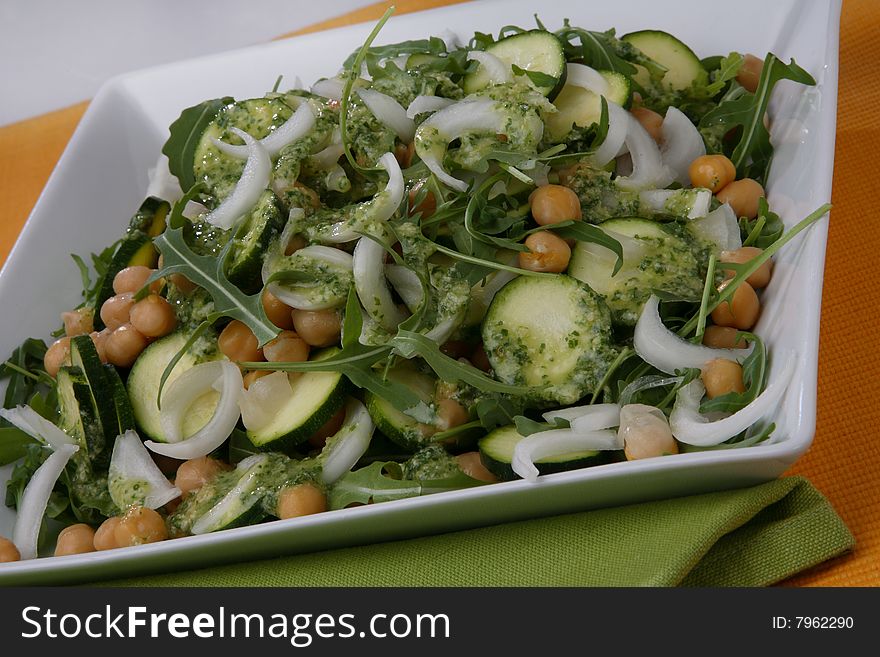 Chick pea, onion, rucola and zuchinni salad with dressing on plate