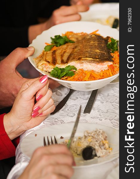 Banquet. Hands hold a plate with a fried salmon.