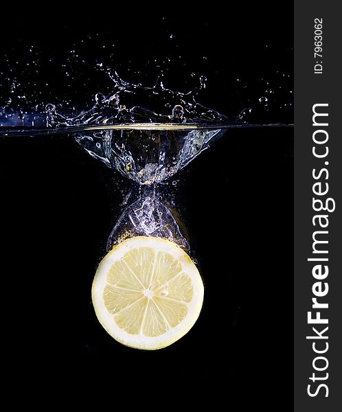 Lemon slice in water with bubbles on black ground. Lemon slice in water with bubbles on black ground