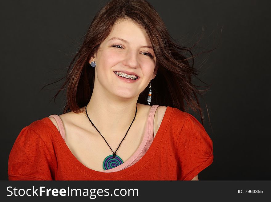 Teenage girl fashion model with red head smiling with brace face with accessories isolated on black. Teenage girl fashion model with red head smiling with brace face with accessories isolated on black