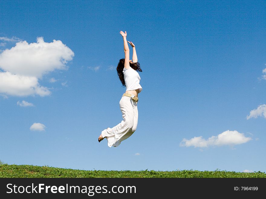 Happy young woman is jumping in green grass