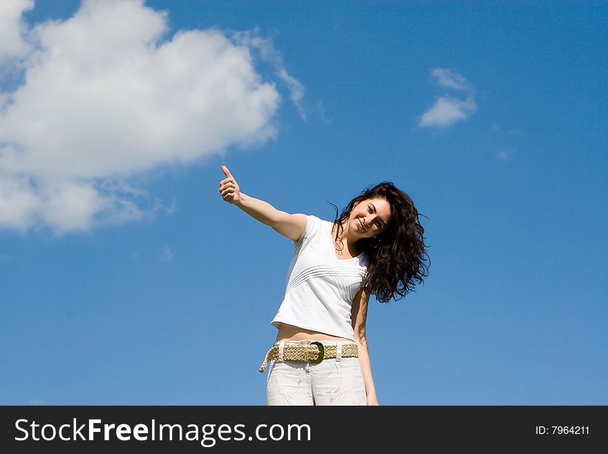 Young woman on a green meadow shows ok sign